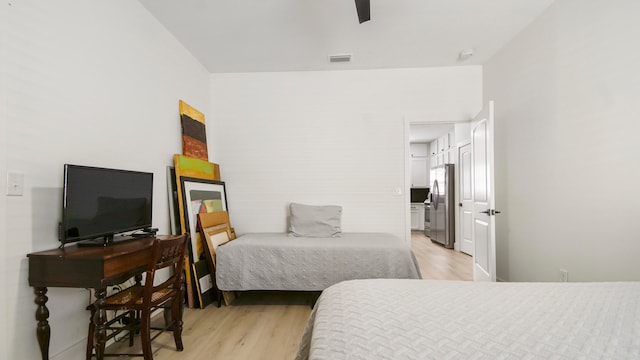 bedroom with ceiling fan, stainless steel fridge, and light hardwood / wood-style flooring