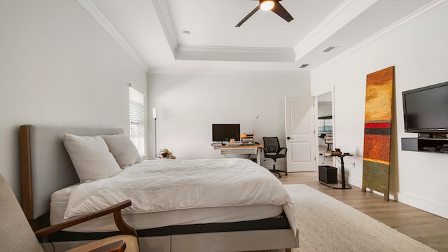 bedroom with a tray ceiling, hardwood / wood-style flooring, ceiling fan, and crown molding