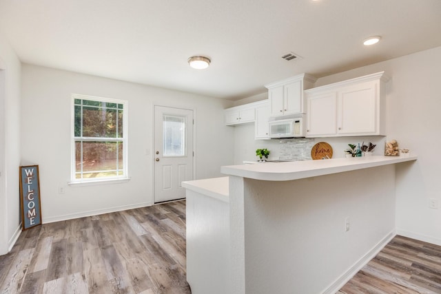 kitchen with white cabinetry, light wood-type flooring, and kitchen peninsula