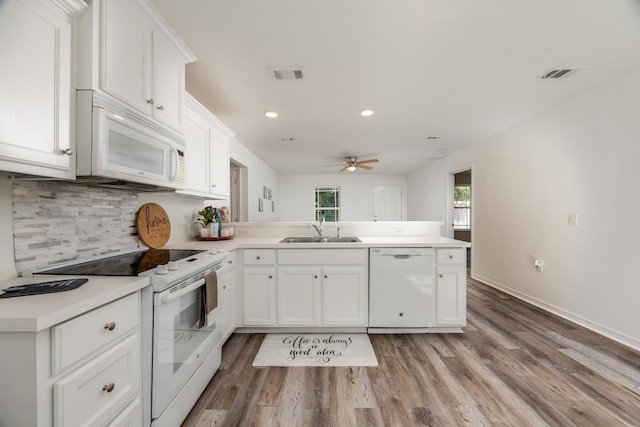 kitchen with kitchen peninsula, white cabinets, light hardwood / wood-style flooring, sink, and white appliances