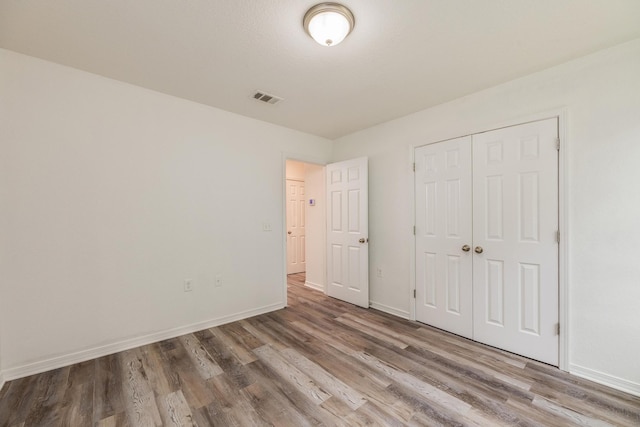 unfurnished bedroom with wood-type flooring and a closet