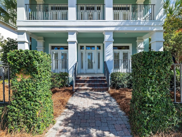 view of exterior entry with french doors and a balcony