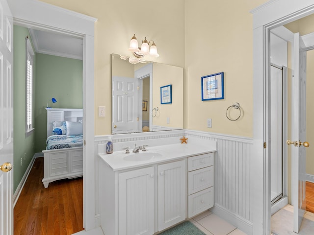 bathroom with a shower with shower door, hardwood / wood-style floors, crown molding, an inviting chandelier, and vanity