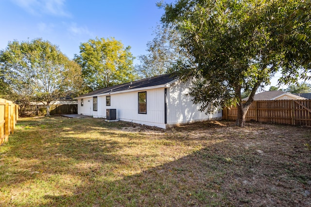 back of house featuring central air condition unit and a lawn