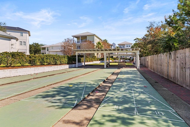 view of home's community featuring fence and shuffleboard