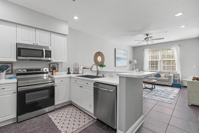 kitchen with appliances with stainless steel finishes, open floor plan, a sink, a peninsula, and tile patterned floors