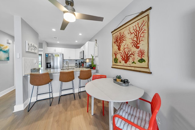 kitchen featuring light stone counters, kitchen peninsula, appliances with stainless steel finishes, white cabinets, and hardwood / wood-style flooring