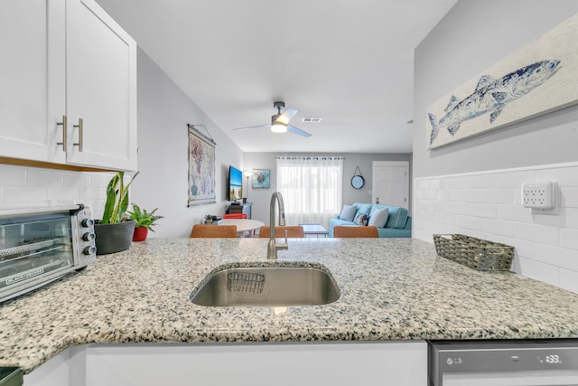 kitchen featuring light stone counters, ceiling fan, sink, dishwasher, and white cabinetry