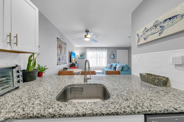 kitchen featuring light stone countertops, tasteful backsplash, white cabinetry, and sink