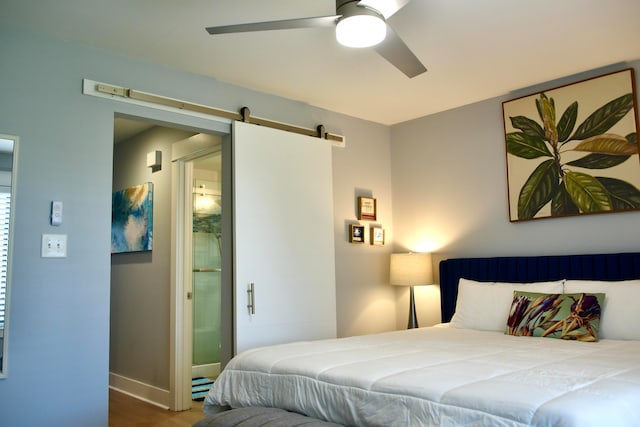 bedroom featuring ceiling fan, a barn door, and wood-type flooring