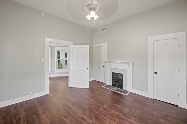 unfurnished living room featuring dark wood-type flooring and ceiling fan