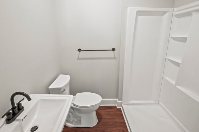 bathroom featuring toilet, hardwood / wood-style flooring, walk in shower, and sink