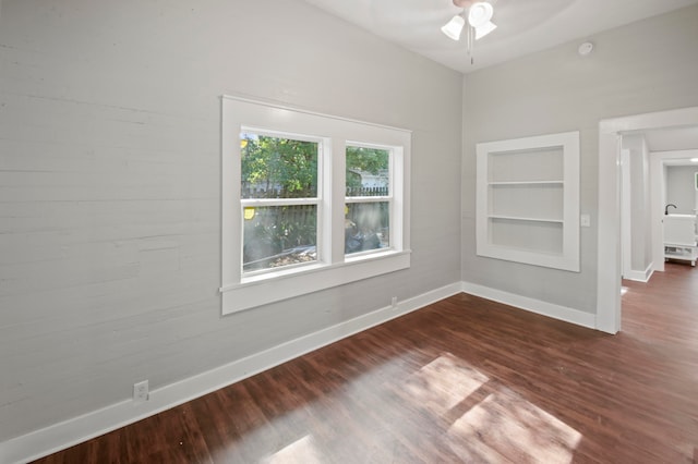 unfurnished room with dark wood-type flooring, ceiling fan, and built in features