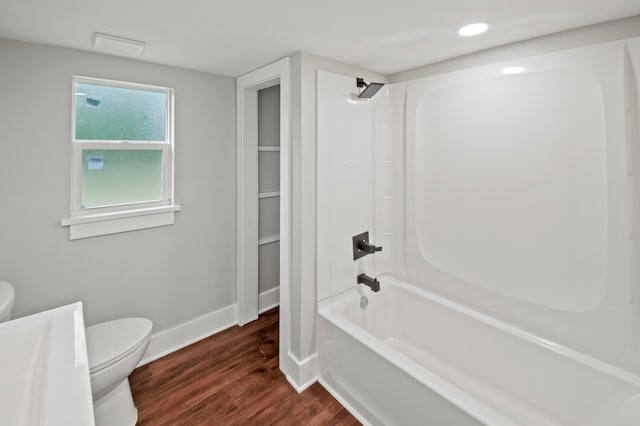 bathroom featuring hardwood / wood-style floors, washtub / shower combination, and toilet