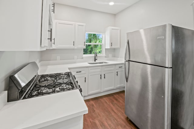 kitchen featuring sink, black gas stove, white cabinetry, stainless steel refrigerator, and dark hardwood / wood-style floors