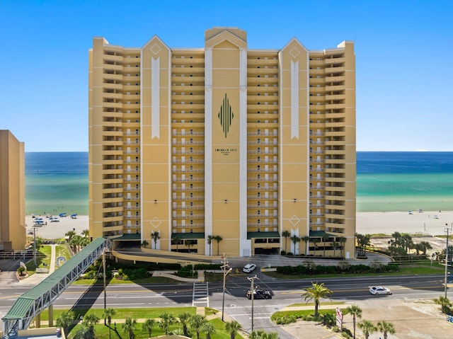 view of building exterior featuring a water view and a beach view