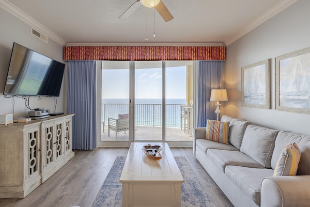 living room featuring a water view, ceiling fan, hardwood / wood-style flooring, and ornamental molding