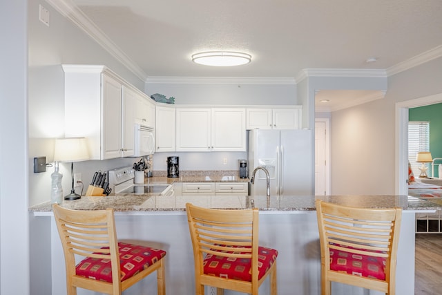 kitchen with a kitchen breakfast bar, white cabinets, and white appliances