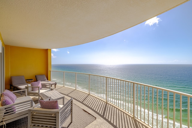 balcony with an outdoor hangout area, a water view, and a beach view