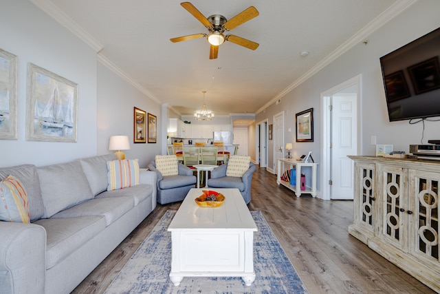 living room with hardwood / wood-style flooring, ornamental molding, and ceiling fan with notable chandelier