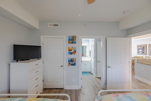 bedroom with connected bathroom and light hardwood / wood-style floors