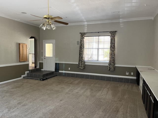 unfurnished living room featuring a textured ceiling, baseboards, carpet flooring, and crown molding