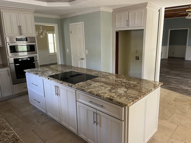 kitchen featuring stone countertops, ornamental molding, a center island, black electric cooktop, and stone tile flooring