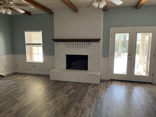 unfurnished living room featuring a healthy amount of sunlight, a wainscoted wall, ceiling fan, and french doors