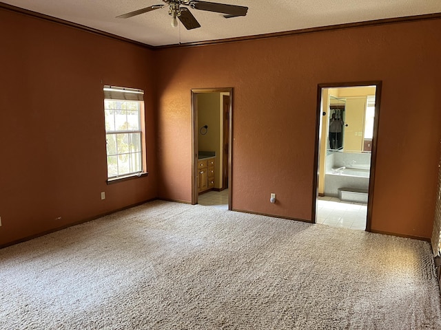 unfurnished bedroom featuring light carpet, a textured wall, crown molding, and ensuite bathroom