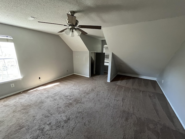 additional living space with lofted ceiling, baseboards, dark carpet, and a textured ceiling