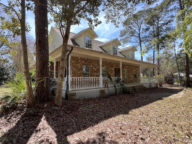 view of front of home featuring covered porch and brick siding