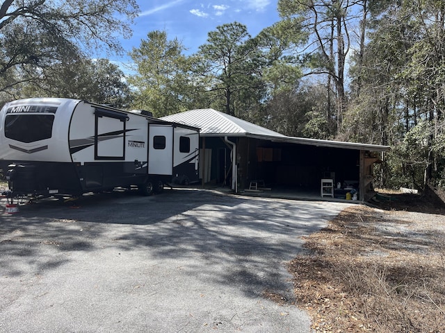 view of front facade featuring aphalt driveway, metal roof, and a carport