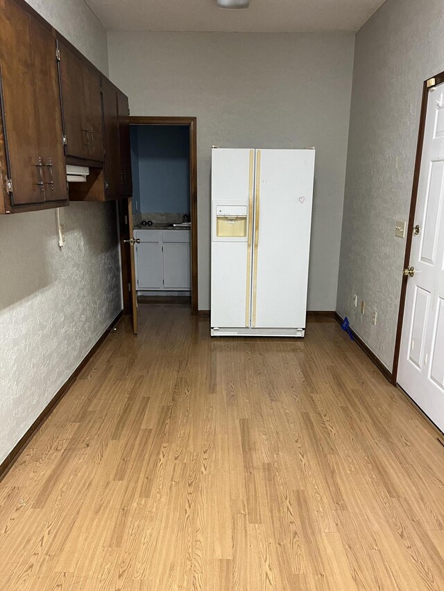 interior space with light wood-style floors, a textured wall, and baseboards