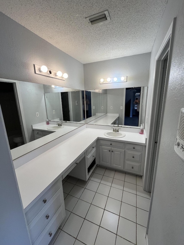 full bath with a textured ceiling, a textured wall, tile patterned flooring, visible vents, and vanity