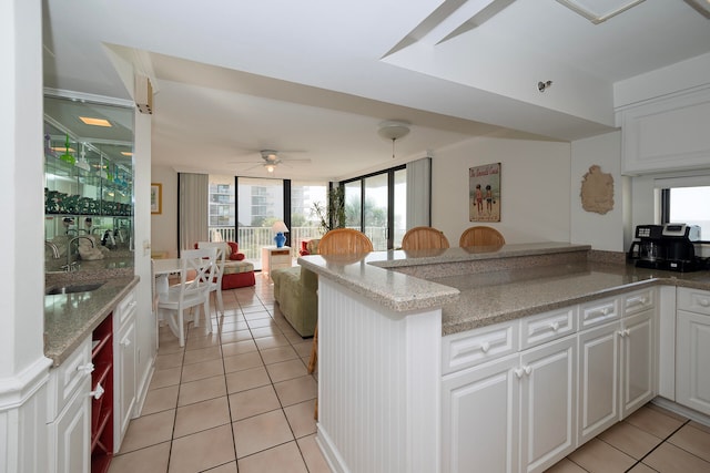 kitchen with kitchen peninsula, white cabinetry, and sink