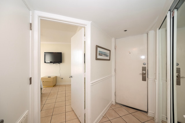 hallway featuring crown molding and light tile patterned floors