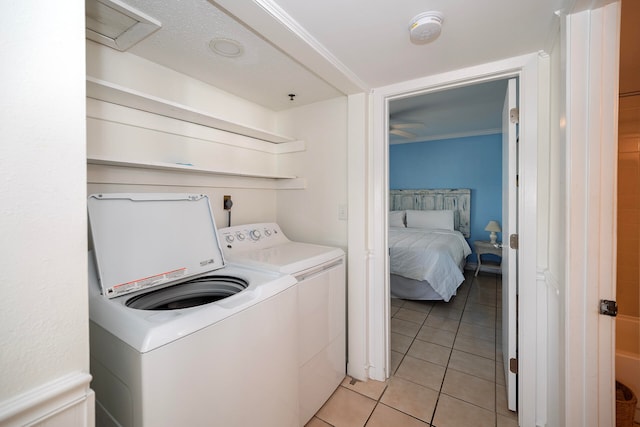 clothes washing area with ornamental molding, washing machine and dryer, and light tile patterned floors