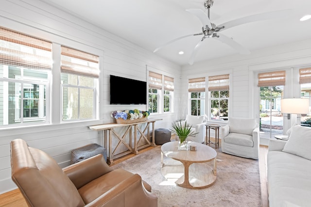 living room with wood-type flooring, ceiling fan, and wooden walls