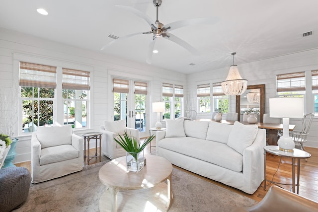 living room featuring ceiling fan with notable chandelier and light hardwood / wood-style floors