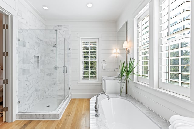 bathroom featuring wood walls, independent shower and bath, hardwood / wood-style floors, and crown molding