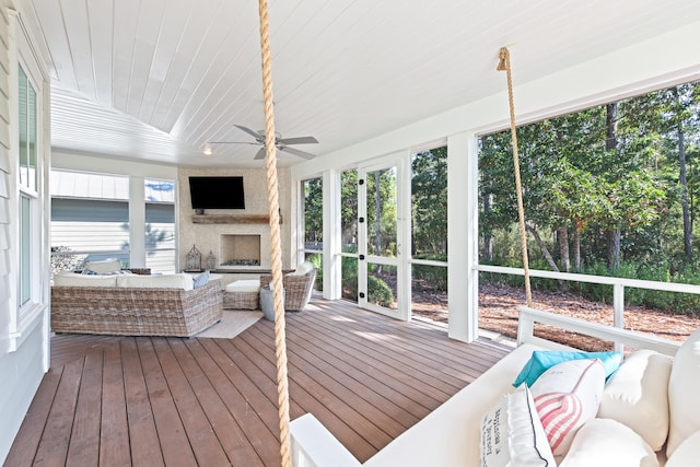 sunroom with a fireplace, ceiling fan, and a healthy amount of sunlight