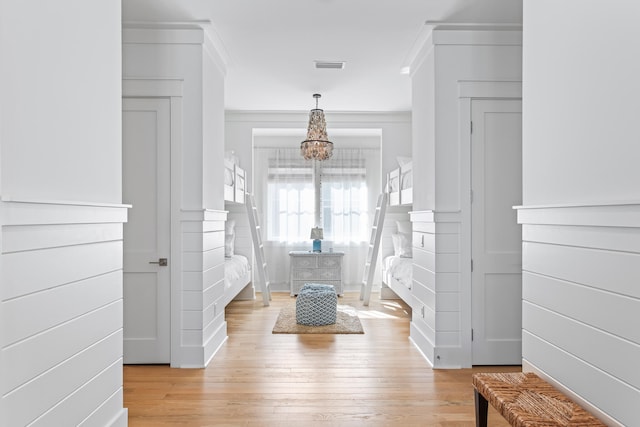 entryway with ornamental molding, light wood-type flooring, and an inviting chandelier