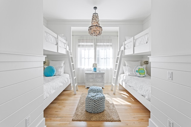 bedroom with ornamental molding, light hardwood / wood-style floors, and a chandelier