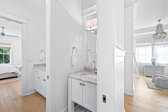 bathroom with ceiling fan with notable chandelier, vanity, and hardwood / wood-style flooring