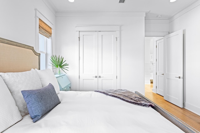 bedroom with wood-type flooring, a closet, and crown molding