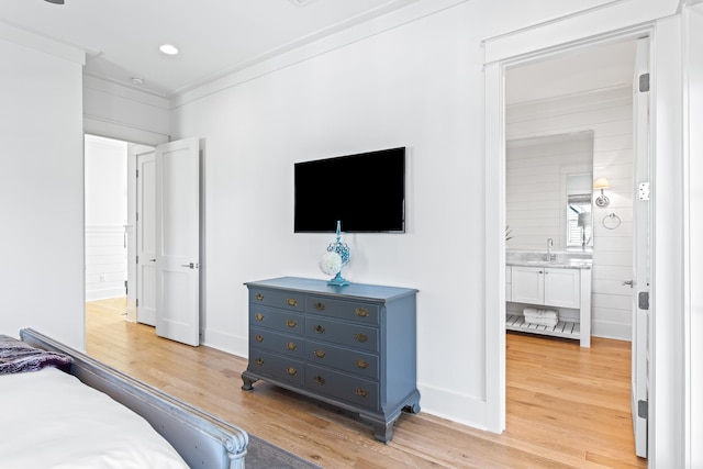 bedroom with ensuite bath, sink, light hardwood / wood-style flooring, and ornamental molding