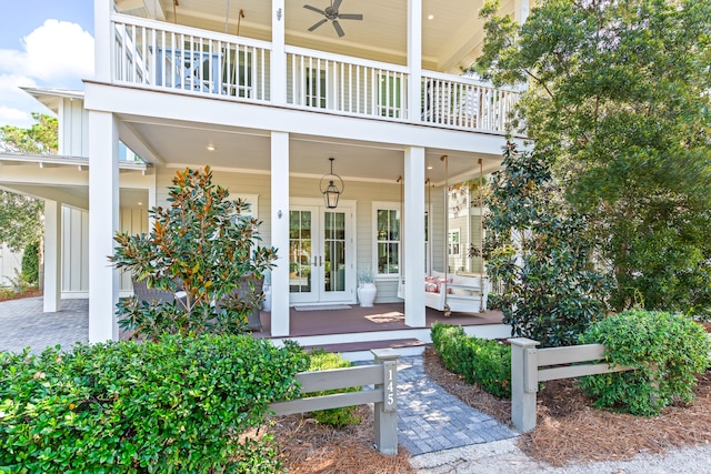 doorway to property with covered porch, a balcony, ceiling fan, and french doors