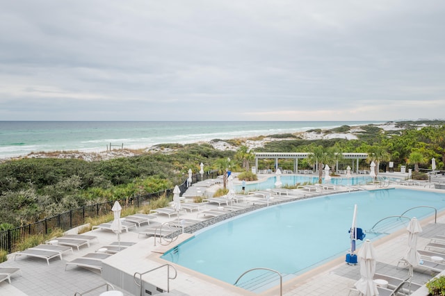 view of pool featuring a patio, a water view, and a view of the beach