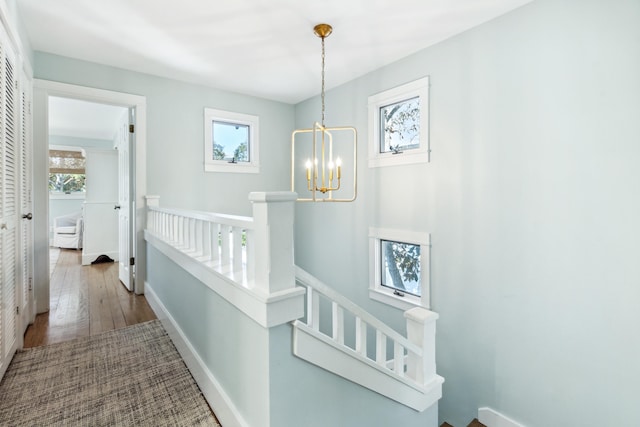 hallway with hardwood / wood-style flooring and a chandelier