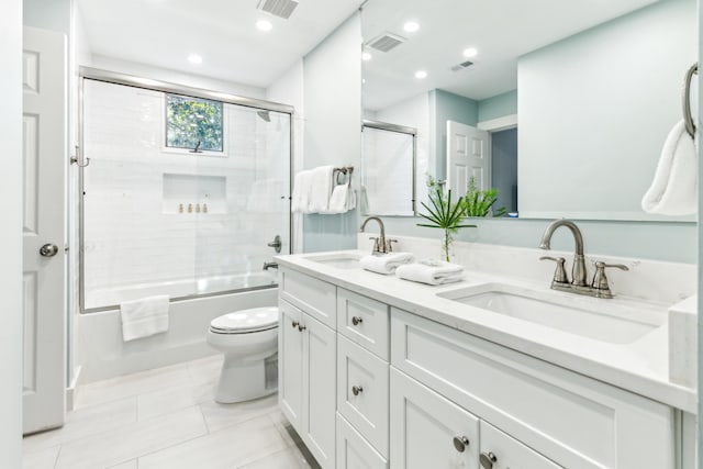 full bathroom with vanity, bath / shower combo with glass door, toilet, and tile patterned flooring